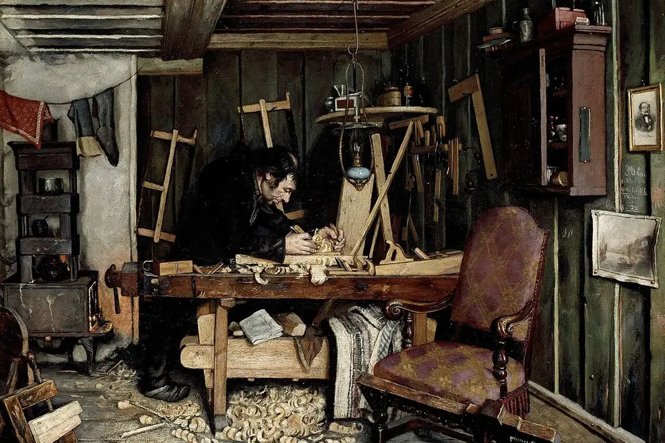 Peinture du XIXe siècle : un menuisier penché sur son établi sculpte une pièce de bois dans un atelier encombré d'outils, de copeaux et de gabarits accrochés aux murs